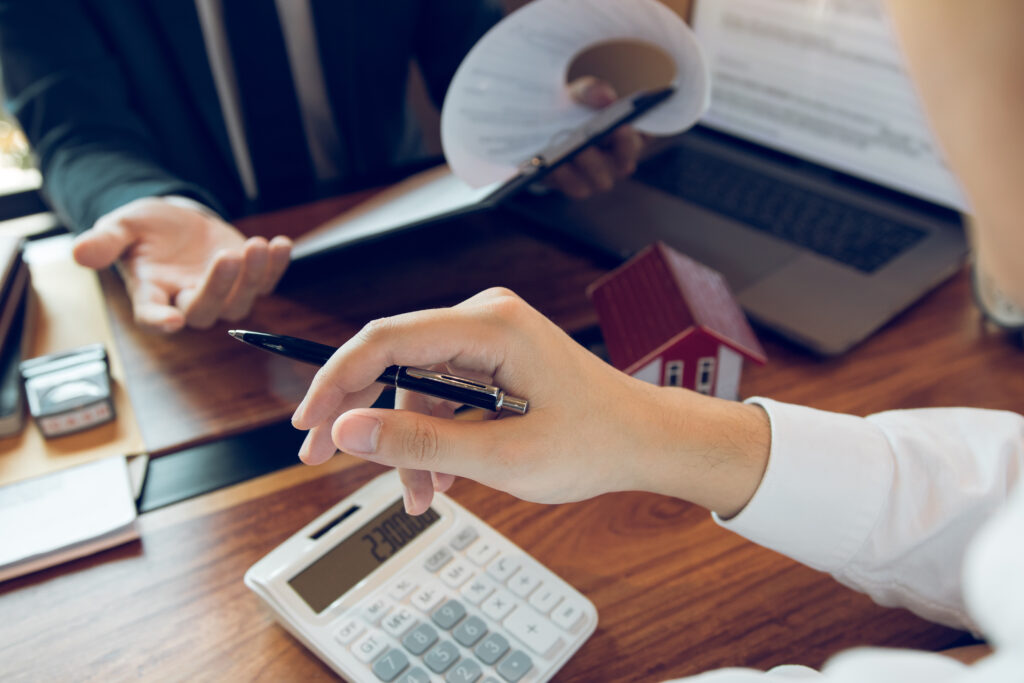 Business people home sales broker is using a pen pointing to the house model and describing the various components of the house.